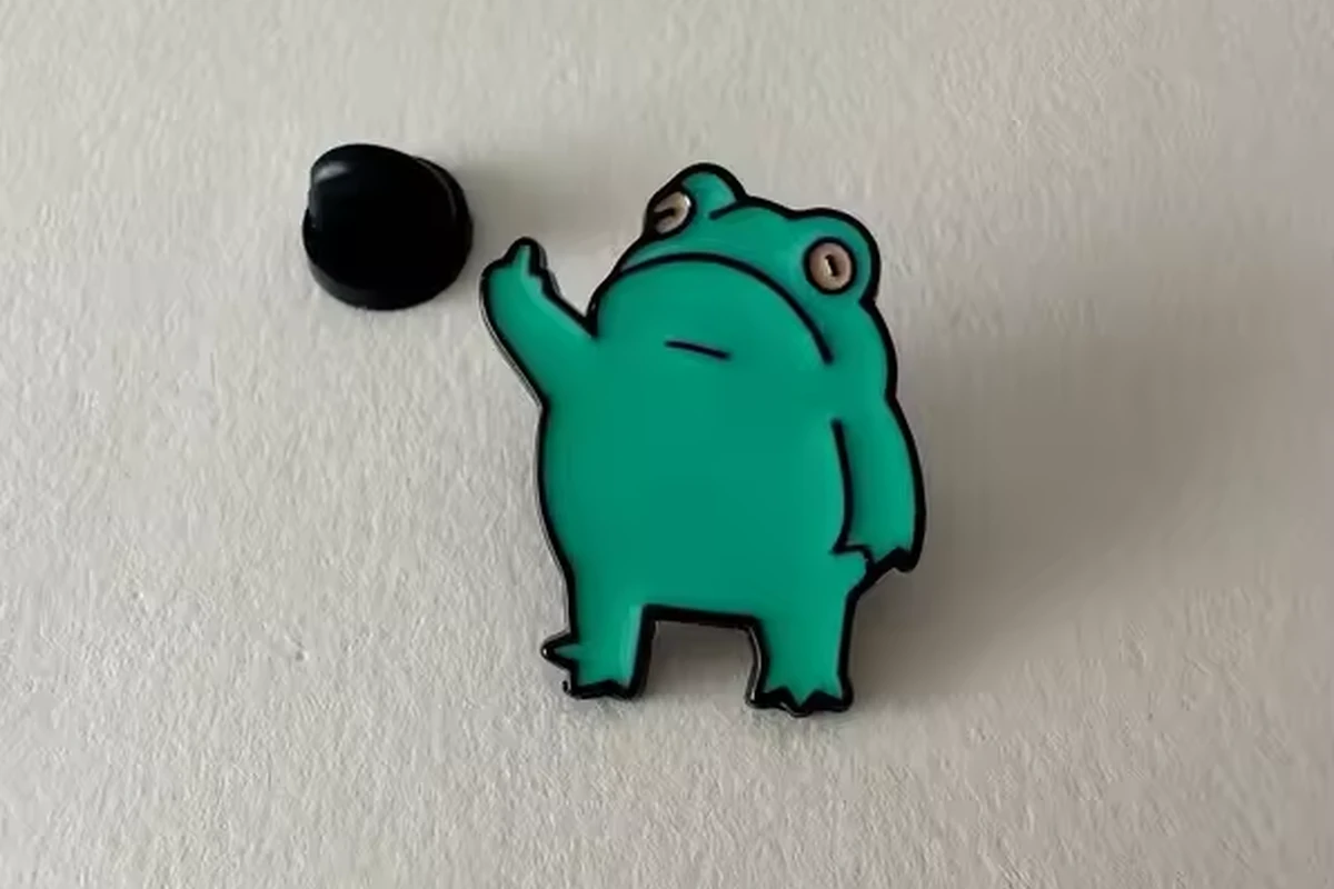 A green frog pin beside a black clutch.